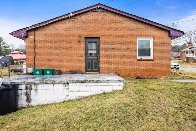 rear view of house featuring a yard and brick siding