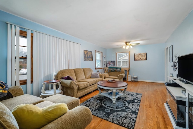 living area featuring light wood-style flooring, baseboards, and a ceiling fan