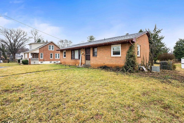 ranch-style house with a front yard, brick siding, and central air condition unit