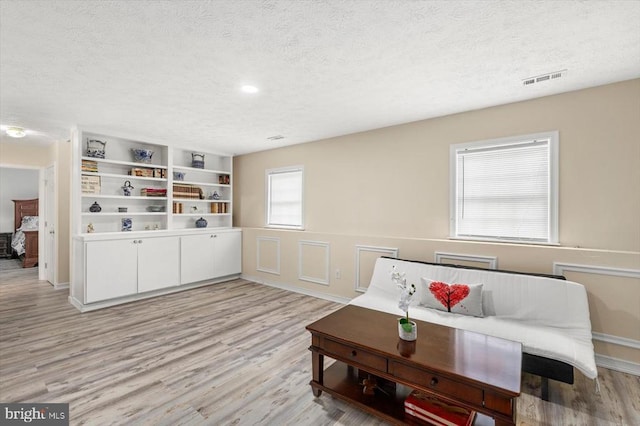 living area featuring a textured ceiling, visible vents, and light wood-type flooring