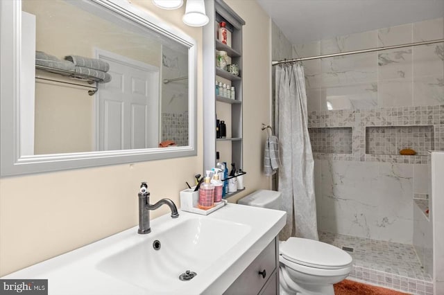 full bath with vanity, a tile shower, and toilet