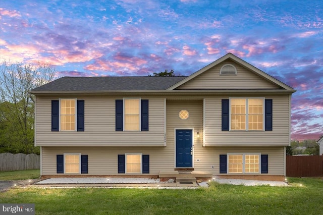 bi-level home featuring a front yard and fence