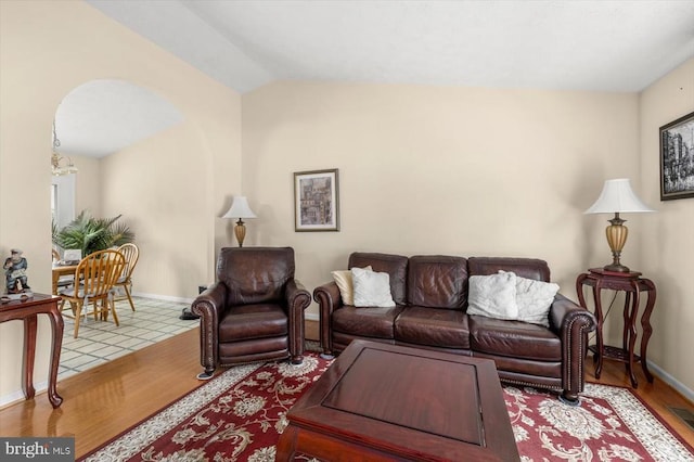 living room with baseboards, wood finished floors, and lofted ceiling