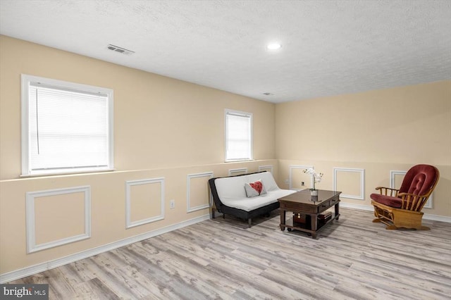 living area featuring a textured ceiling, wood finished floors, visible vents, and recessed lighting