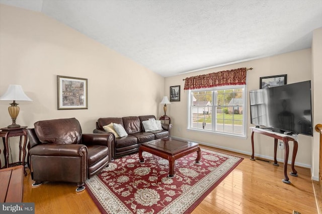 living room featuring light wood-style flooring, baseboards, vaulted ceiling, and a textured ceiling
