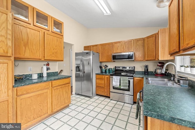 kitchen featuring dark countertops, a sink, lofted ceiling, and stainless steel appliances