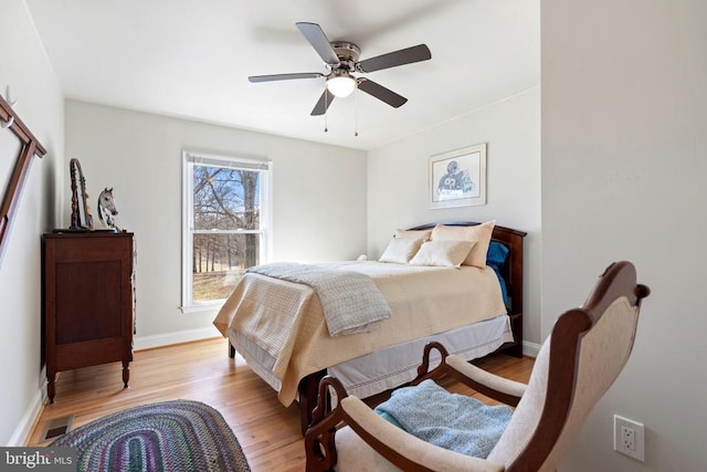 bedroom featuring ceiling fan, visible vents, baseboards, and light wood-style flooring