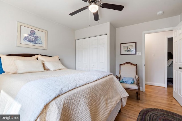 bedroom with a closet, baseboards, light wood-style floors, and ceiling fan