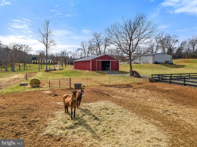 view of yard with an outbuilding, a detached garage, fence, a rural view, and a pole building