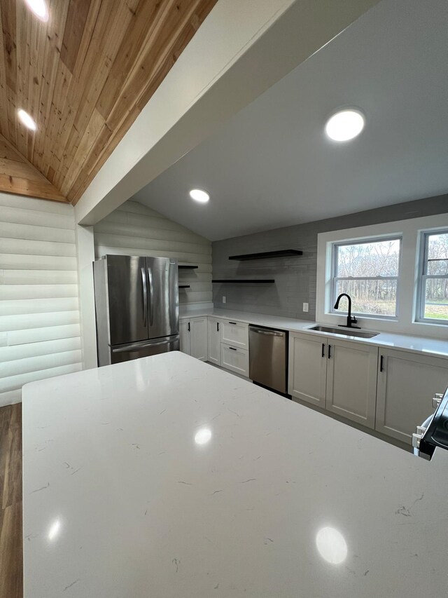 kitchen with vaulted ceiling, appliances with stainless steel finishes, sink, white cabinets, and wooden ceiling