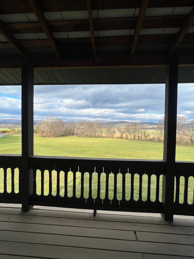 wooden terrace featuring a rural view and a yard