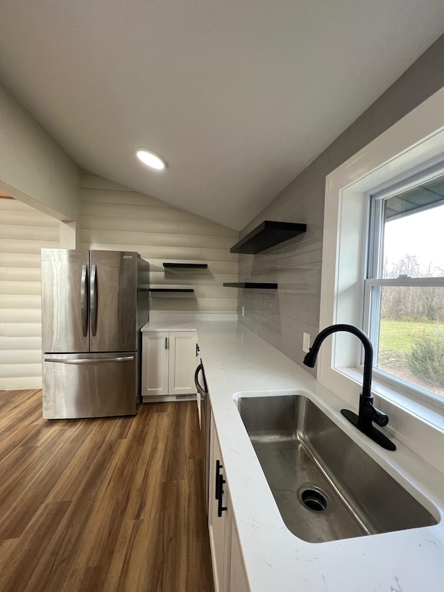 kitchen featuring dark wood-type flooring, lofted ceiling, sink, white cabinetry, and stainless steel fridge