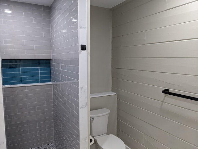 bathroom featuring tiled shower and toilet