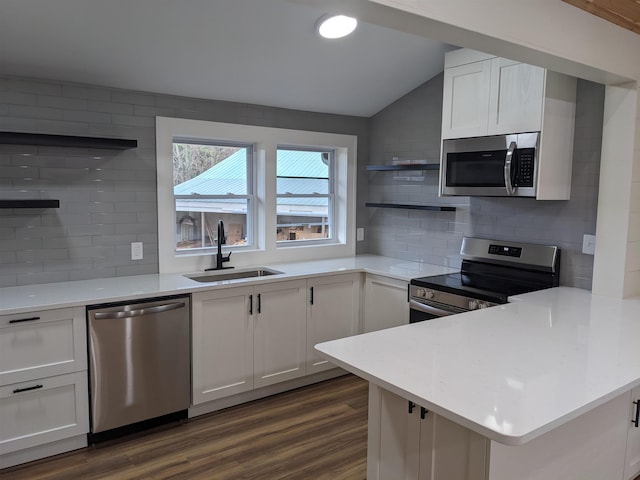 kitchen featuring sink, white cabinetry, stainless steel appliances, dark hardwood / wood-style floors, and vaulted ceiling