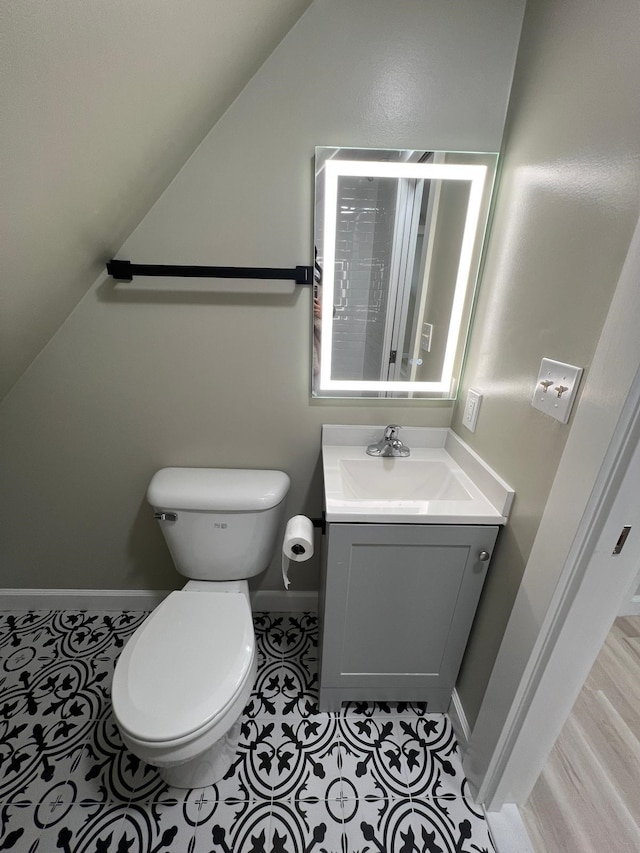 bathroom featuring vanity, vaulted ceiling, tile patterned floors, and toilet