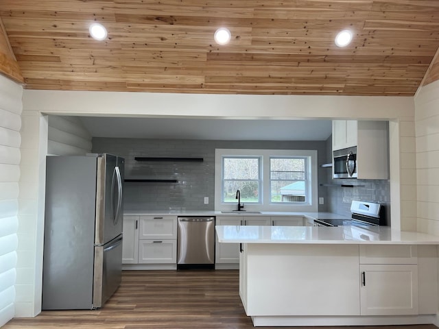 kitchen featuring vaulted ceiling, appliances with stainless steel finishes, sink, white cabinets, and kitchen peninsula