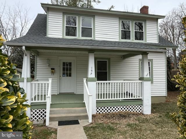 view of front of property with covered porch, roof with shingles, and a chimney