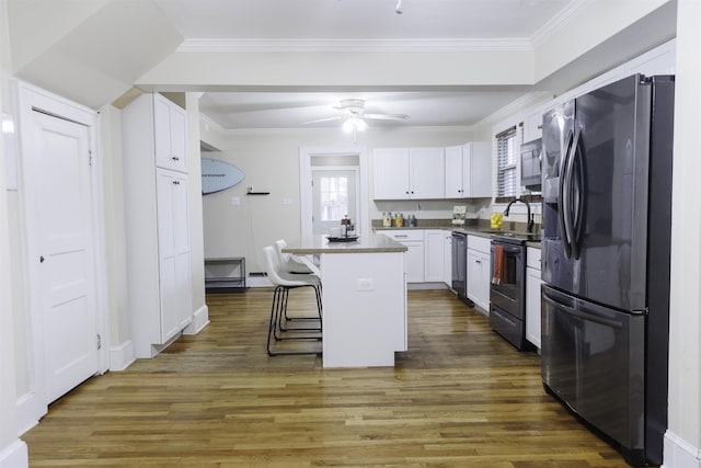 kitchen featuring appliances with stainless steel finishes, dark hardwood / wood-style floors, a breakfast bar, white cabinetry, and a center island