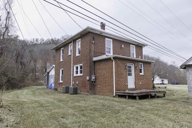 rear view of house with central AC and a lawn