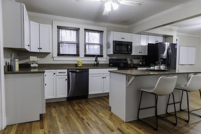 kitchen featuring a kitchen island, appliances with stainless steel finishes, white cabinetry, ornamental molding, and dark wood-type flooring