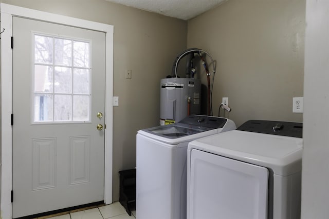 laundry area with light tile patterned floors, electric water heater, and washing machine and clothes dryer