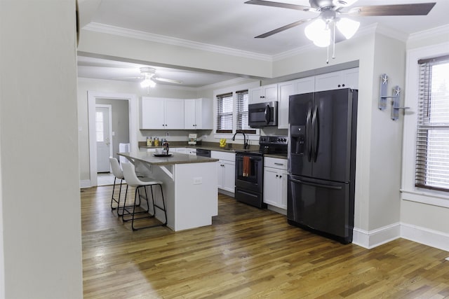 kitchen featuring dark wood-type flooring, a breakfast bar, a center island, appliances with stainless steel finishes, and white cabinets