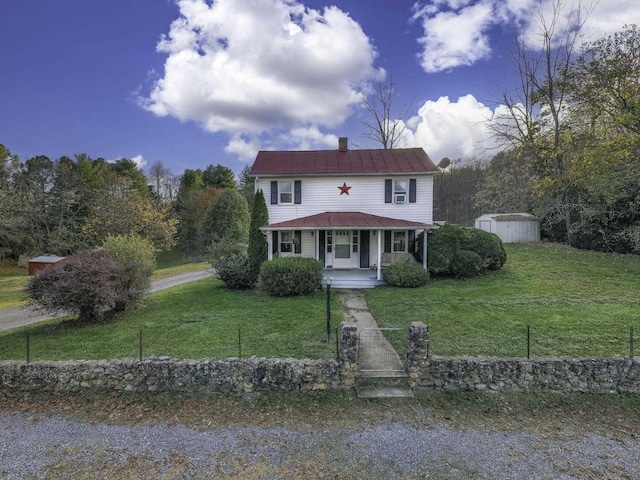 view of front of property featuring a storage unit, a porch, a front yard, and an outbuilding