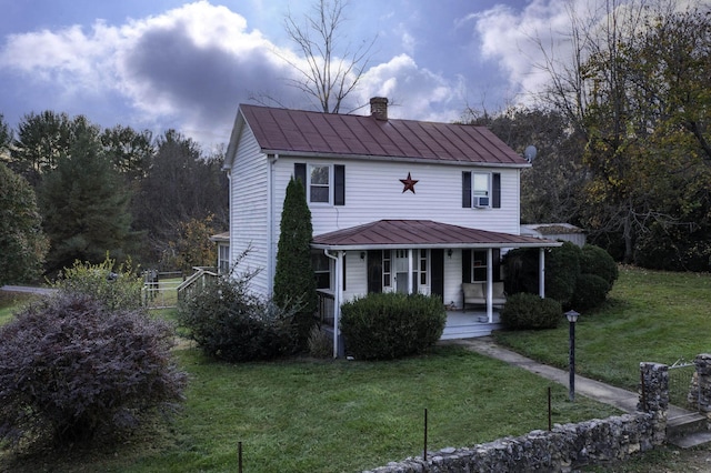 view of front facade with a standing seam roof, metal roof, covered porch, a chimney, and a front yard