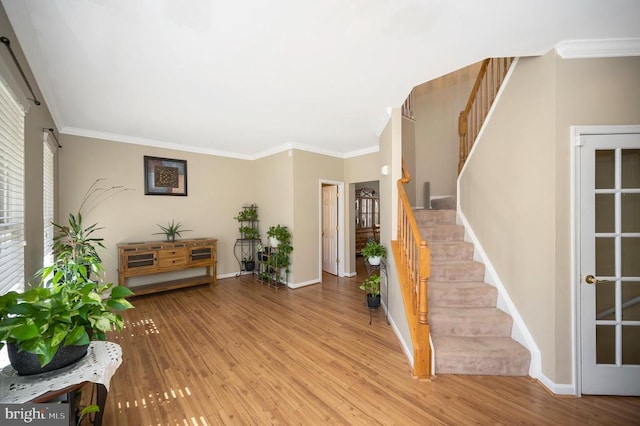 foyer featuring stairs, ornamental molding, baseboards, and wood finished floors