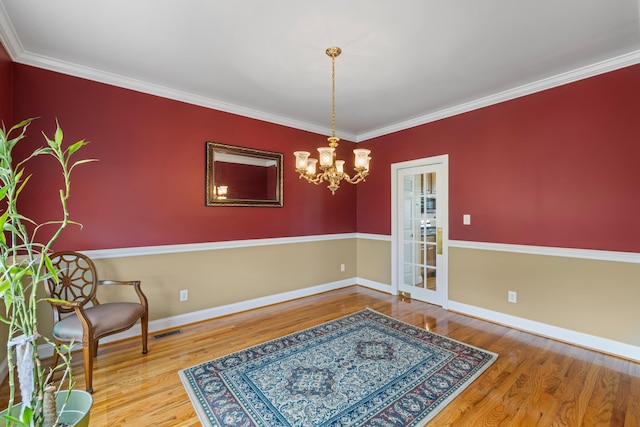 living area with crown molding, wood finished floors, baseboards, and a chandelier