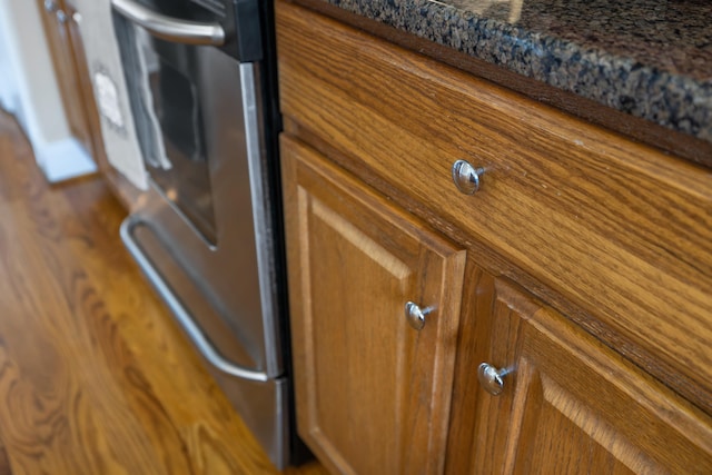 details with dark stone countertops, brown cabinets, and stove