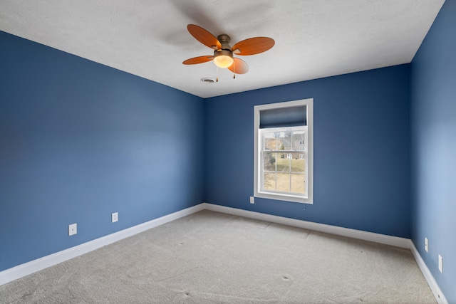 carpeted empty room with visible vents, a textured ceiling, a ceiling fan, and baseboards