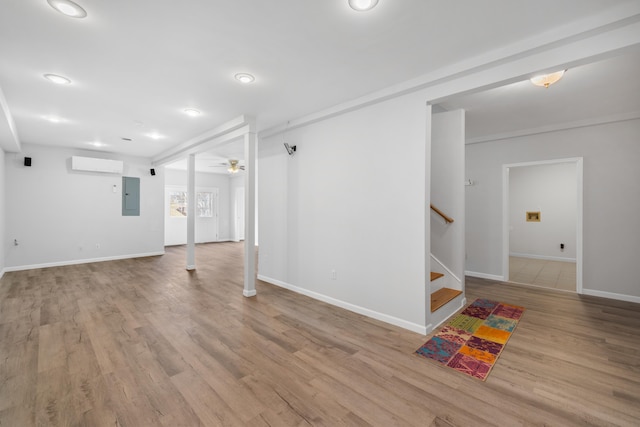 below grade area featuring wood finished floors, baseboards, electric panel, stairs, and a wall mounted air conditioner