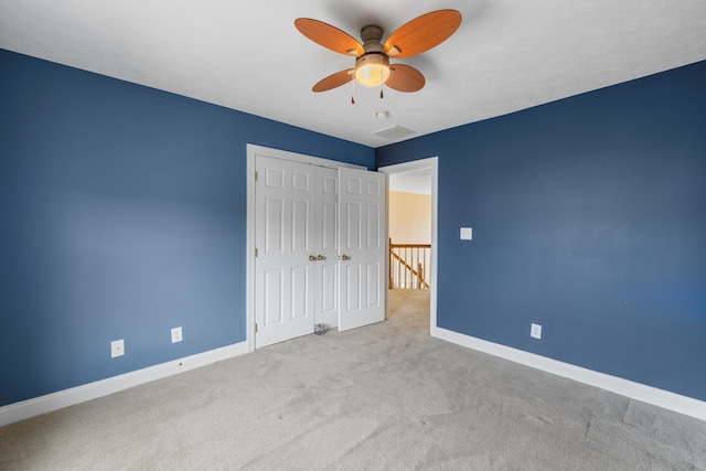 unfurnished bedroom featuring visible vents, a closet, carpet, baseboards, and ceiling fan