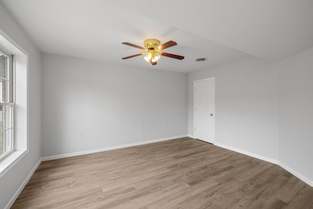 empty room with visible vents, ceiling fan, baseboards, and wood finished floors