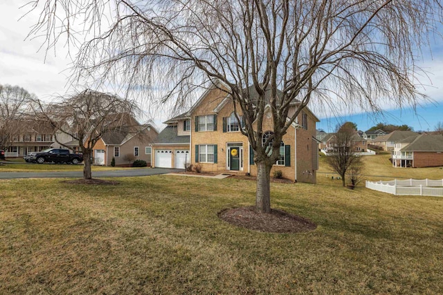 view of front of property with aphalt driveway, fence, a residential view, a front yard, and brick siding