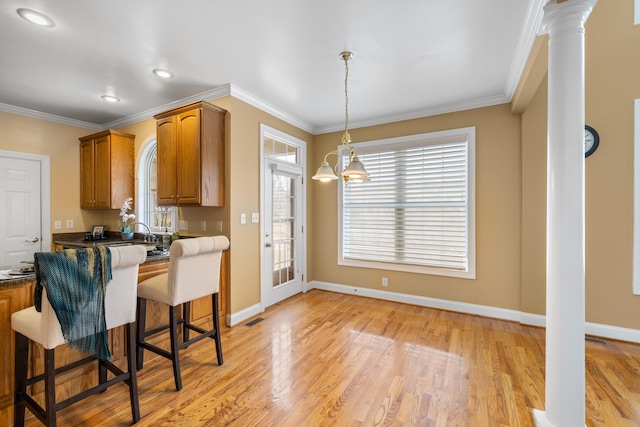 kitchen featuring crown molding, dark countertops, brown cabinetry, and light wood-style floors