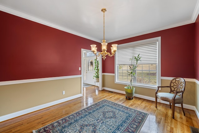 living area with baseboards, a notable chandelier, wood finished floors, and crown molding