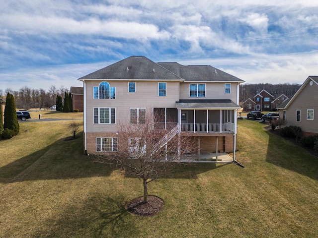 back of property featuring stairway, a lawn, brick siding, and a sunroom