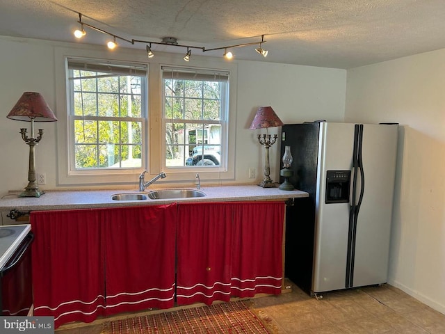 kitchen featuring range, stainless steel fridge with ice dispenser, sink, and a textured ceiling