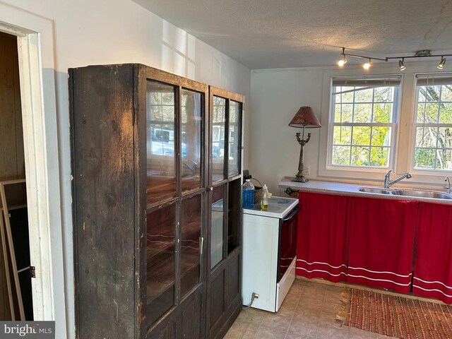 kitchen with white electric range, rail lighting, sink, and a textured ceiling