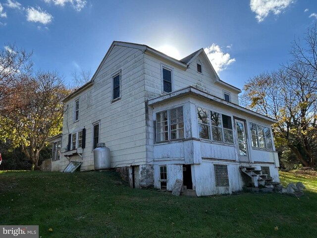 view of home's exterior with a lawn and a sunroom