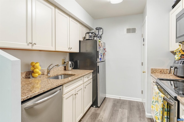 kitchen featuring visible vents, appliances with stainless steel finishes, light wood-style floors, white cabinetry, and a sink