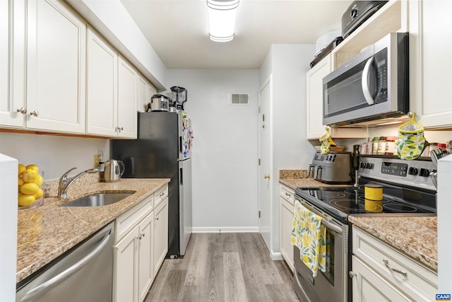 kitchen featuring stainless steel appliances, visible vents, light wood-style flooring, white cabinetry, and a sink