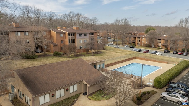 community pool featuring central air condition unit, a residential view, and fence