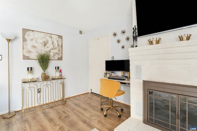 office area with a fireplace, wood finished floors, visible vents, and baseboards