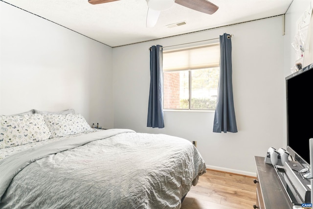 bedroom with a ceiling fan, baseboards, visible vents, and wood finished floors