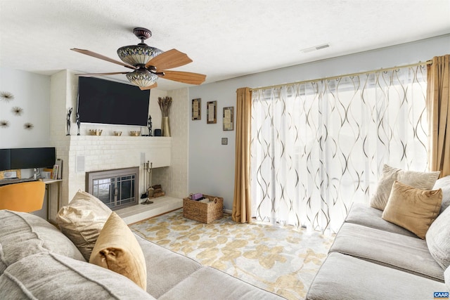 living room with a textured ceiling, a fireplace, visible vents, and a healthy amount of sunlight