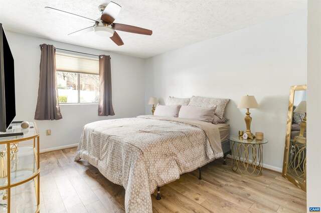 bedroom featuring a textured ceiling, light wood-style flooring, and baseboards