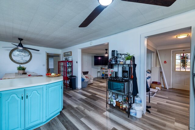 kitchen with blue cabinetry, ceiling fan, and light hardwood / wood-style floors